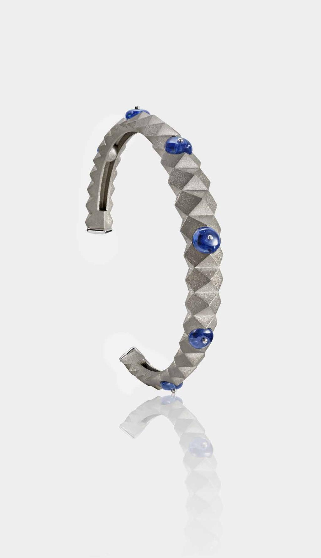 Reza Titan Rigide bangle in sand blasted white gold with blue sapphires Olivier Reza follows in the steps of his Iranian father Alexandre, lauded as one of the greatest gem collectors of modern times