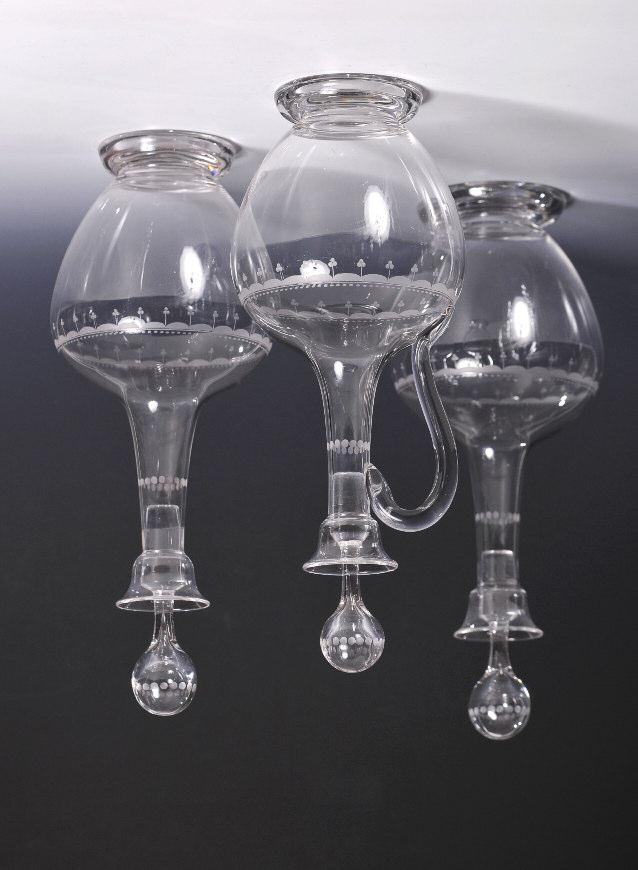 19th Century Decanters No. 381 $995 TRIO: pair and claret jug with loop handle, ball stoppers, everted cup lips, footed plain ewer bodies, engraved decorative bands at neck and shoulders.