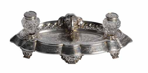 Lot 274 Victorian London silver inkwell stand by Elder and Co. London 1856, of scalloped oval form cast with an elephants head between two detachable silver and crystal inkwells.