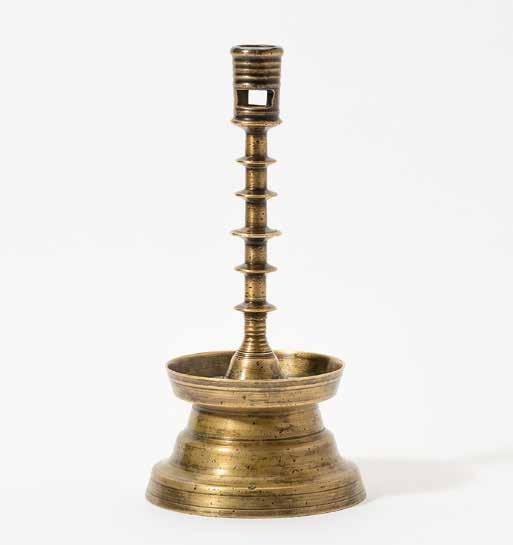 190 A Dutch brass candlestick 16th century With a rimmed and pierced nozzle, a disc knobbed stem