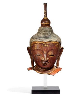 The design of the face typical of the Shan tradition with almost closed eyes and a smiling mouth. The stylized ears with long earlobes. At the neck part of the garment in light red lacquer preserved.