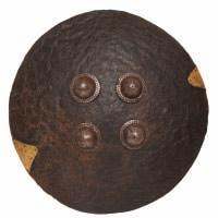 76 A RARE INDIAN ELEPHANT HIDE SHIELD, DHAL, 17TH CENTURY of shallow convex circular form, the outer face fitted with four large domed steel bosses with chiselled bases decorated with a scale