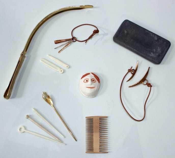 Personal Care Artefacts in Trunk Cosmetic palette and spatula Cosmetic grinder Bronze cosmetic set Bone tweezers Bone scoop Antefix Styling head and clamp Wooden combs x 2 Hairstyling booklet Beauty
