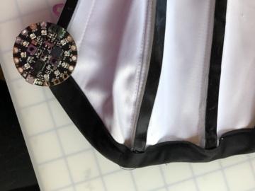 Most corsets have a privacy flap at the back to cover the inside of the laces. This is a perfect spot to put your battery.