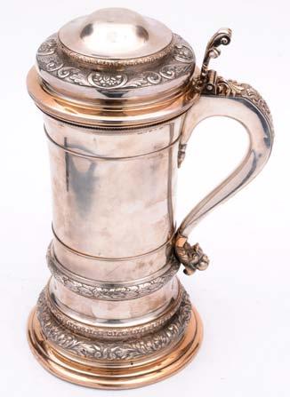 A Swedish tankard of tapered cylindrical form, leaf capped scroll handle, the body and semi domed cover decorated with foliate scroll banding, on shouldered circular foot, the body and cover
