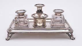 A late Victorian inkstand, of rectangular form, gadrooned border with two pen wells and central circular seal box, surmounted by a half fluted urn