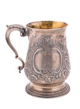 A Victorian tankard of baluster form on a spreading circular base, scroll handle and chair back thumbpiece to the domed cover, embossed and
