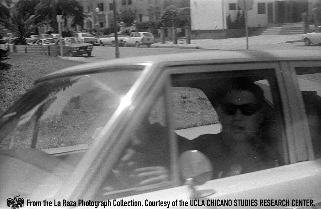 LAPD officer in car during a Vietnam protest La Raza