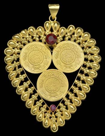 36 AN ARABIC GOLD PENDANT, of heart-shaped form with raised detail, stylized coin motifs and red paste highlights, yellow precious metal, bale stamped MAW, 21C, pendant length 9cm, gross weight 21.