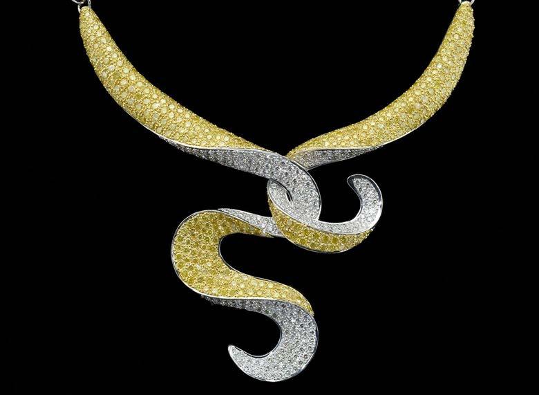 234 A YELLOW AND WHITE DIAMOND SET NECKLACE, the scrolled ribbon form centrepiece pave set with yellow and white brilliant-cut diamonds, with pierced fretwork back, to a polished tapered bowed-link