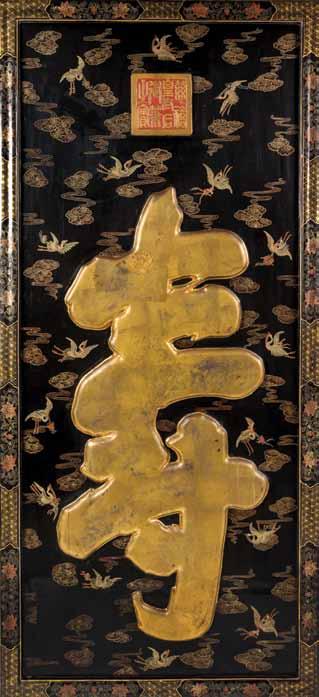 112 112* A Chinese Lacquered Panel, having raised gilt-painted shou, on a black ground with cranes and beribboned Buddhist and Daoist