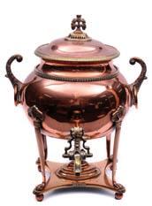 A Regency copper tea urn of oval form, the domed lid with foliate finial, with foliate ring handles to the sides, raised on four reeded