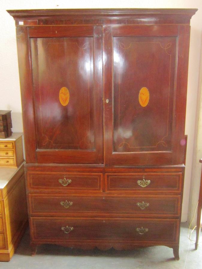 458. An Edwardian inlaid mahogany Dressing chest, the shield shaped bevelled swing mirror flanked by trinket drawers and with two long drawers below and raised on four squared tapering supports,