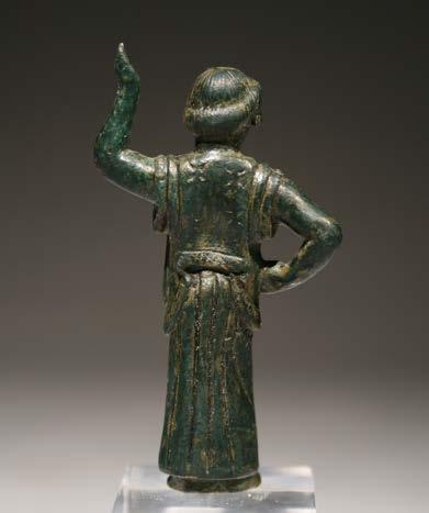 She may have carried a water vessel originally (as a hydrophoros or hydria carrier). Her peplos is richly decorated with four-pointed stars and cross-hatched trim. Her muscular arms are uncovered.