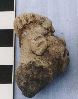 Because of the hairstyle and head decoration, this head may be female. Each of the ears has two grooves rather than punctations. The face is oval with the chin sticking out.