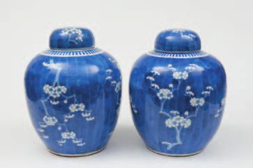 100-200 545 A pair of large Chinese ovoid jars and covers painted with gnarled prunus branches reserved in white against a deep blue foliate ground, apocryphal four-character Kangxi marks, 19th