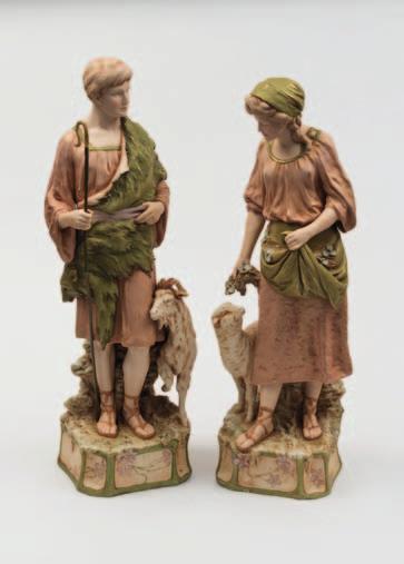 150-200 616 A pair of Royal Dux Bohemia porcelain figures of a goat herder and shepherdess both in standing posture, he dressed in an animal skin