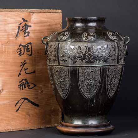 Height 11 Width 10 1010 十九世纪铜仿古兽面纹双系鱼篓尊 A CHINESE BRONZE VASE A bronze antique Chinese vase. This highly decorative amphora-styled vessel has a circular, segmented base with a raised, engraved boss.