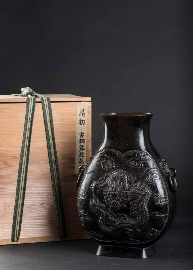1002 清铜云龙纹铺首方瓶 A BRONZE DRAGON VASE A Chinese bronze vase. In a flattened rectangular shape, the vase has a single pedestal base and a rounded rectangular neck.