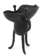 531 533 532 531 An Archaistic Bronze Wine Vessel, Jue CHENGHUA PERIOD (1465-1487) the deep body raised on three splayed legs, the sides cast with a wide band of geometric designs, having a C-scroll