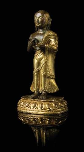 583 583 A Sino-Tibetan Gilt Bronze Figure of a Standing Buddhist Monk 18TH-19TH CENTURY the igure cast standing on a lotus base, wearing long robes draped over his left shoulder, the right hand