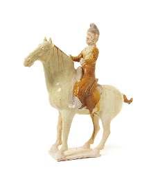 59 61 59* A Glazed Pottery Equestrian Figure POSSIBLY TANG DYNASTY depicting a male igure dressed in amber toned loose robes, his both hands raised, riding on a