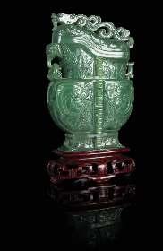 283 A Carved Spinach Jade Covered Vase 20TH CENTURY of an even colored green stone with black speckles, of archaistic form with the lattened body raised on a splayed foot, each side carved in relief