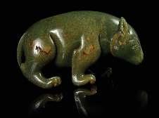 317 A Carved Celadon Jade Figure of a Recumbent Horse the stone of a greyish green tone, the animal depicted with all four tucked underneath the body, the head turned to the left with carved eyes,