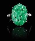 $1,000-2,000 387 A Jadeite and Diamond Inset Ring the apple green and celadon stone pierced and carved with loral scrolls. Length 5/8 inches.