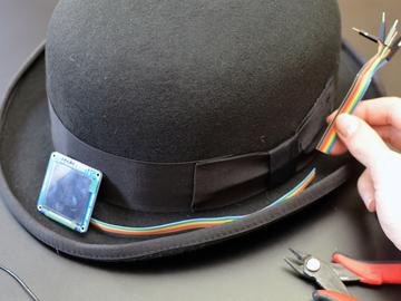 Fold the ribbon cable at a right angle to send it out one side toward the hat's ribbon bow.