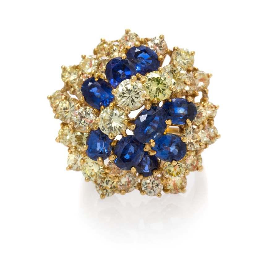Lot 238 An 18 Karat Yellow Gold, Platinum, Colored Diamond and Sapphire Cluster Ring, Oscar Heyman Brothers, in an open wirework design, containing 33 round brilliant cut yellow diamonds (origin of