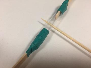 straw piece that is between two popsicle sticks.