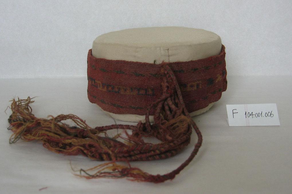 The warps are 2-ply Z-spun S-twist. The outer face of the band is mostly red with three stripes of blue, yellow, green, red, tan, and brown designs.