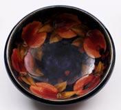 A Moorcroft pottery bowl of circular form tube lined in the Pomegranate pattern in red, russet and green on a graduating green blue ground, 24 cm diameter, impressed Moorcroft, Made