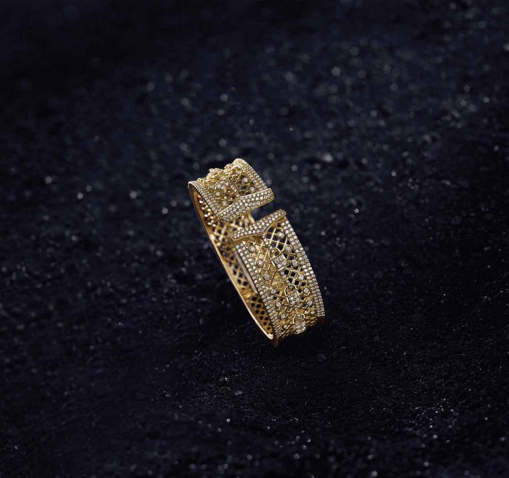 Tiny locks dangle from the yellow gold mesh of this open-top bangle.