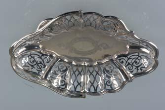 Lot 133 Lot 133 A LATE VICTORIAN WAVY OVAL SILVER CAKE BASKET, with pierced serpentine swing handle, the panelled sides with foliate scrolls and other patterns, the centre with vacant