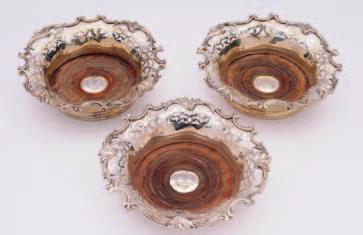 A set of three Victorian wine coasters, circular form, pierced foliate scroll borders, wooden bases set with