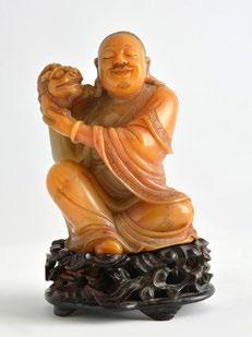 134 Steatite sculpture depicting a seated and smiling Luohan with a dragon on