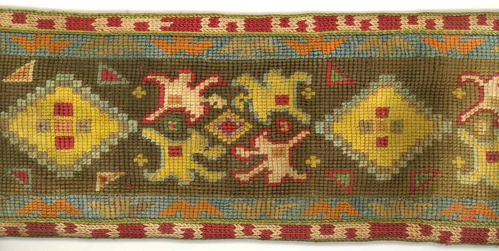 Wide belt embroidered overall in multi-colored diamond and leaf motifs on brown field, edged in band of S motifs, lined in