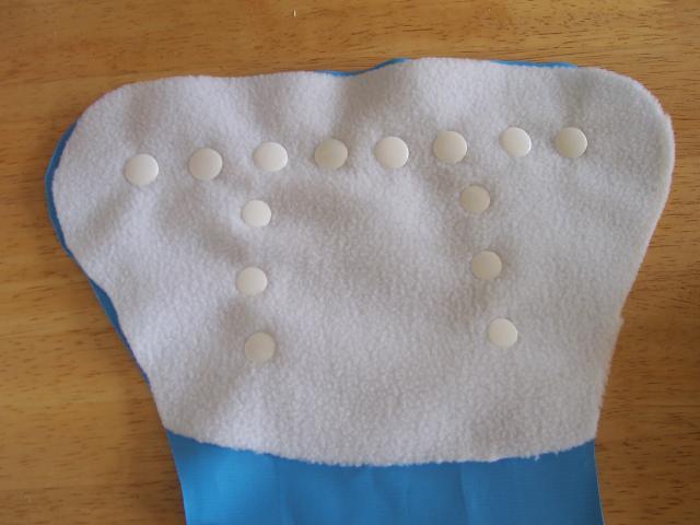 TUMMY FASTENINGS 1. Place the reinforcement scrap of fabric onto the wrong side of the PUL nappy piece. Secure with pins or bull dog clips or spring clothes pegs. 2.