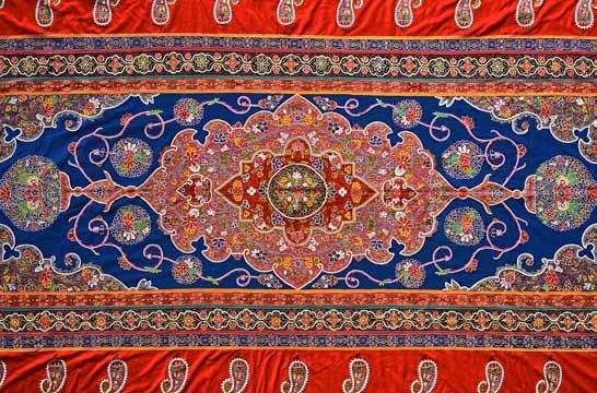 1130. A large embroidered hanging, Rescht, Persia, 20th century, the main deep blue field with central lobed medallion with polychrome floral design, similar spandrels, the scarlet red main border
