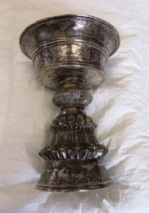 It is chalice-shaped, with a slightly flared bowl and bell-shaped base. There are decorative marks around the bowl and base, and there is a bulging ring on the stem between the bowl and base.