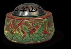 ) A rare pottery incense burner decorated with a riverside profusion of mizu-bashō [water plantain] and reeds, the shibuichi cover pierced with a continuous design of the artist s name, Hanzan, four