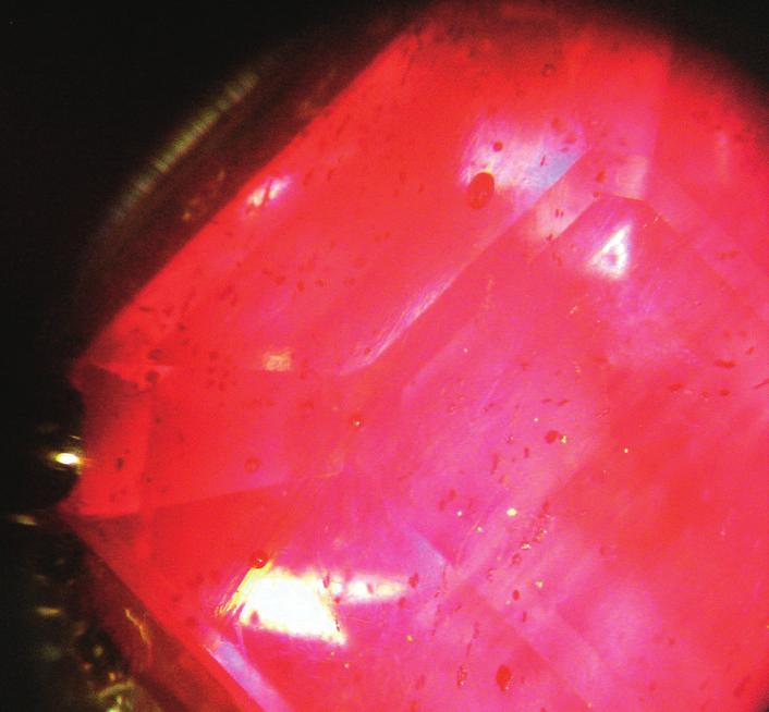 Glass-filled ruby with surface fractures and blue-orange flash.
