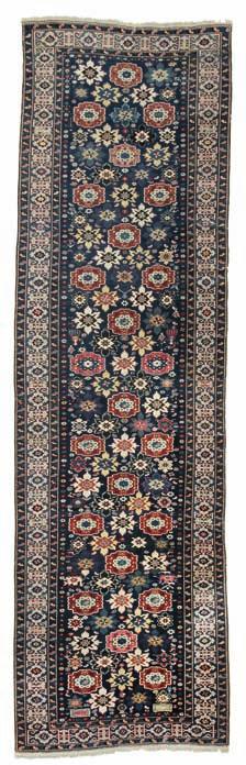 309 an antique Kuba-shirvan blossom runner, caucasus. all over design of staggered stylised flower heads on a blue field with human figures, jugs and star motifs surrounded by cufic main border.