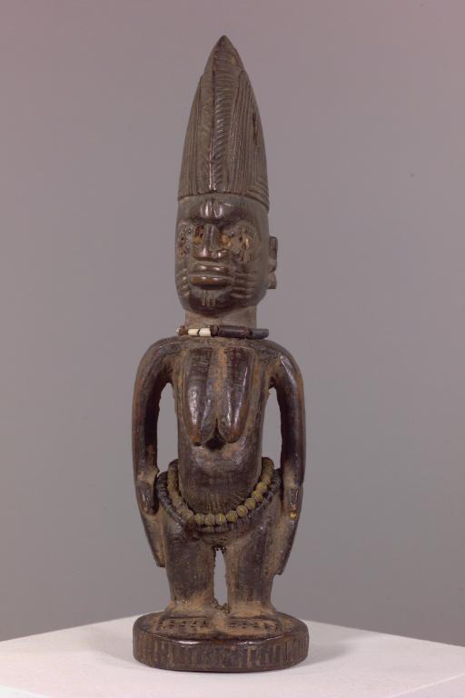 Fig. 3. Unknown Yoruba artist (Nigeria), Female Twin Figure (ère ìbejì), date unknown. Wood, with mound base, long breasts, scarifications, tall coiffure, and strands of beads, 28.