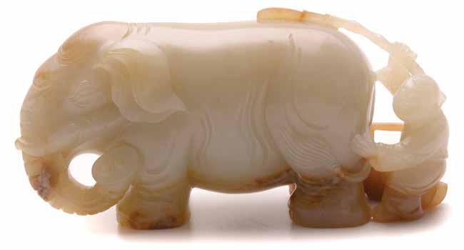 Lot 6022 6022 A Jade Carving of an Elephant With a boy brushing the standing elephant s back, the stone of pale green tone with russet inclusions. Length: 5 inches (12.