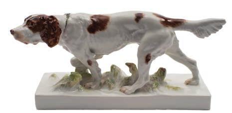 * 300-500 643 A Meissen porcelain model of an Irish red and white setter in pointing pose with one front leg raised, on rectangular grassy mound base, underglaze blue crossed swords