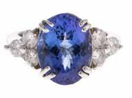 JEWELRY 350 354 358 A Lady s Tanzanite & Diamond Ring in 18K Gold 18K white gold ring showcasing a vibrantly hued oval tanzanite weighing approx 630 cts, in an 8 prong mounting flanked by a trio of