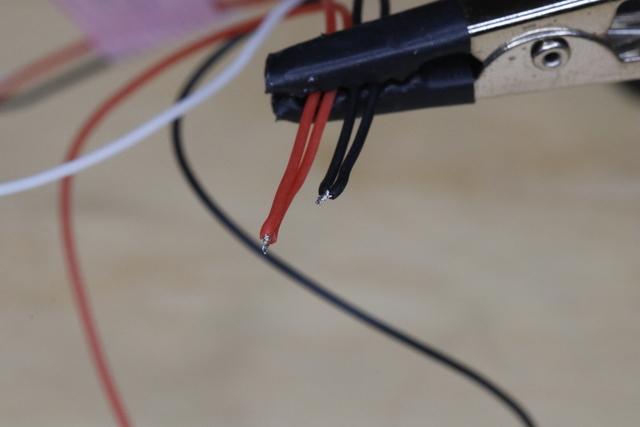 Use tweezers to twist the two power (or ground) wires together tightly. Tin the twisted wires.
